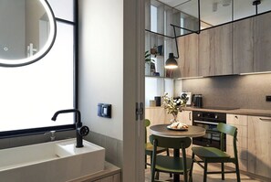 A modern kitchen with a round dining table, a built-in oven, and a hanging pendant light. - Riverside Gdańsk Apartment by Lion Apartments (Gdańsk)