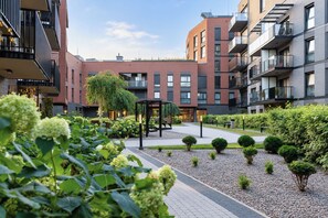 A modern building with a courtyard featuring a gazebo, benches, and well-maintained greenery. - Riverside Gdańsk Apartment by Lion Apartments (Gdańsk)