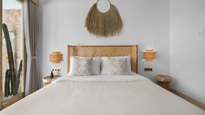 Un letto con testiera intrecciata, due abat-jour e un elemento decorativo a parete.