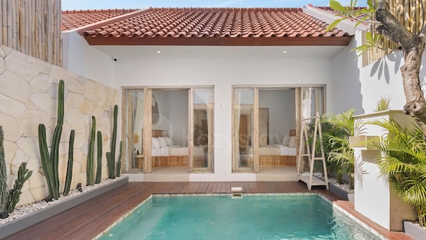 Una piscina con un pontile in legno, un muro bianco decorato con un motivo esagonale e una recinzione in bambù.