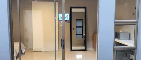 A room with a sliding door, a television, a microwave, and a cabinet.