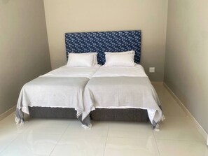 A double bed with a patterned headboard, two pillows, and a grey bedspread. - Room-nest24 Evans Park Private & Cosy Gu (Johannesburg)