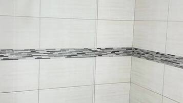 Un área de ducha con paredes de azulejos y un cabezal.