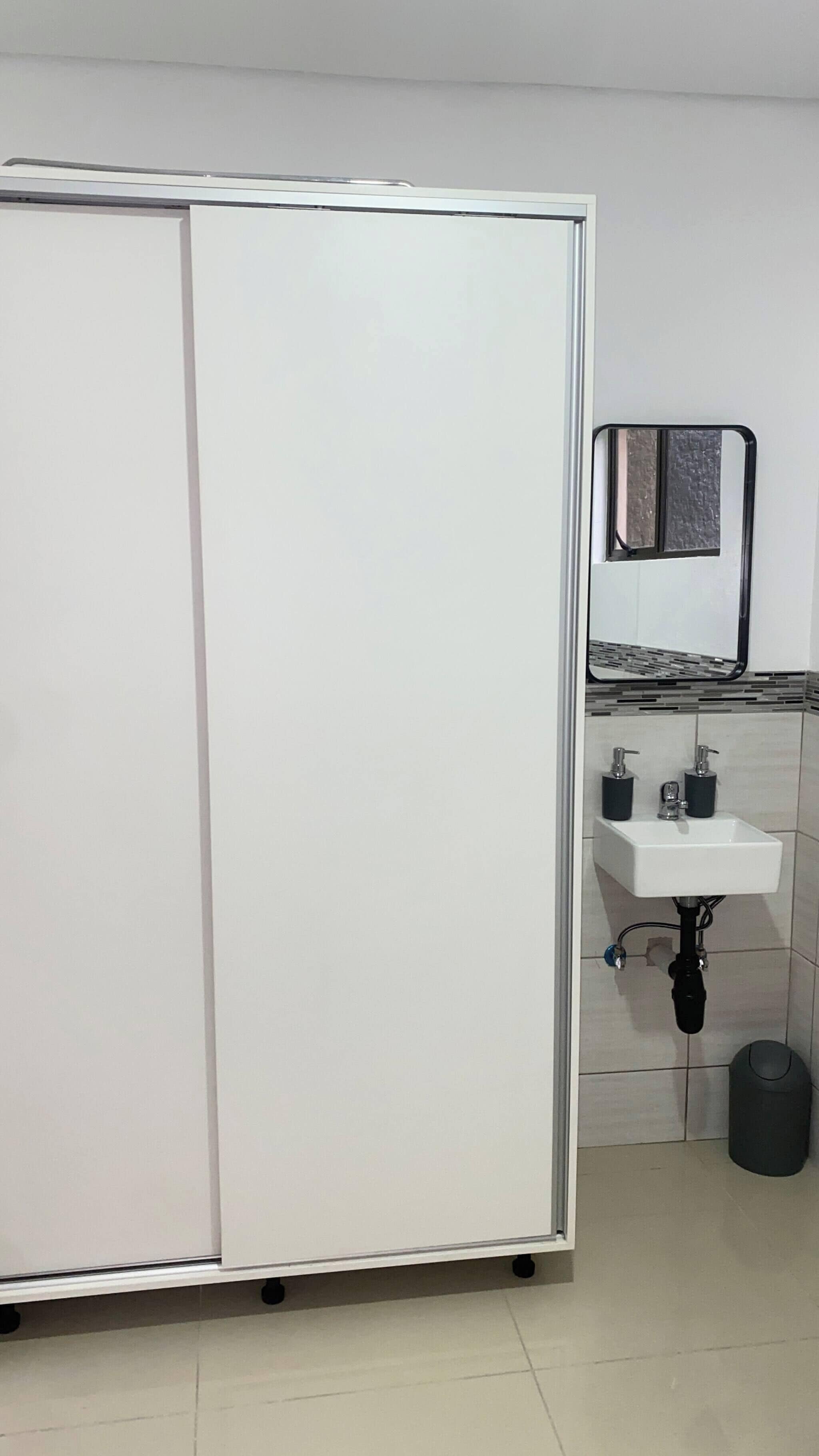 Un baño con lavamanos blanco, un espejo y un inodoro.