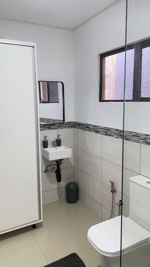 Un baño pequeño y limpio con inodoro, lavamanos y ducha.