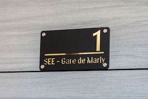Segnale nero con scritte dorate che indica la stanza numero 1 e il nome 'SEE - Gare de Marly'.