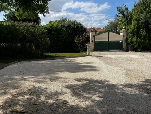A gravel driveway leading to a gated entrance with a building in the background. - Holiday Home 'Maison Bord’Eau -  Bord De Dordogne' with Shared Garden, Wi-Fi and Air Conditioning (Saint-André-de-Cubzac)