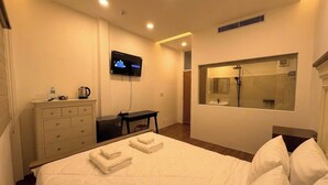 Ein Hotelzimmer mit Bett, Schreibtisch, Fernseher, Spiegel und Duschbereich.
