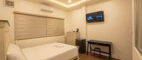 Une chambre d’hôtel avec un lit, un bureau, une chaise, une télévision et une fenêtre.
