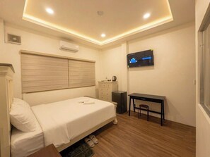 Una habitación de hotel con una cama, un escritorio, una silla, un televisor y una ventana.