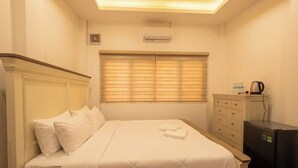 Ein Hotelzimmer mit einem Bett, einem Schminktisch, einem Heizkörper und einem Fenster mit Jalousien.