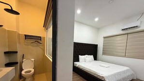 Ein Badezimmer mit Toilette, Dusche und einem Bett mit Kopfteil und Fenster.
