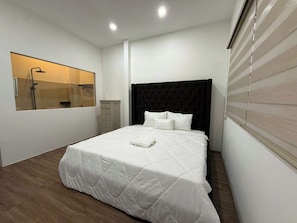 Un dormitorio moderno con una cama grande, un armario empotrado y una ventana con persianas.