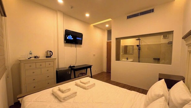 Ein Hotelzimmer mit einem Bett, einem Fernseher, einem Schreibtisch, einem Spiegel und einem Badezimmer mit Dusche.