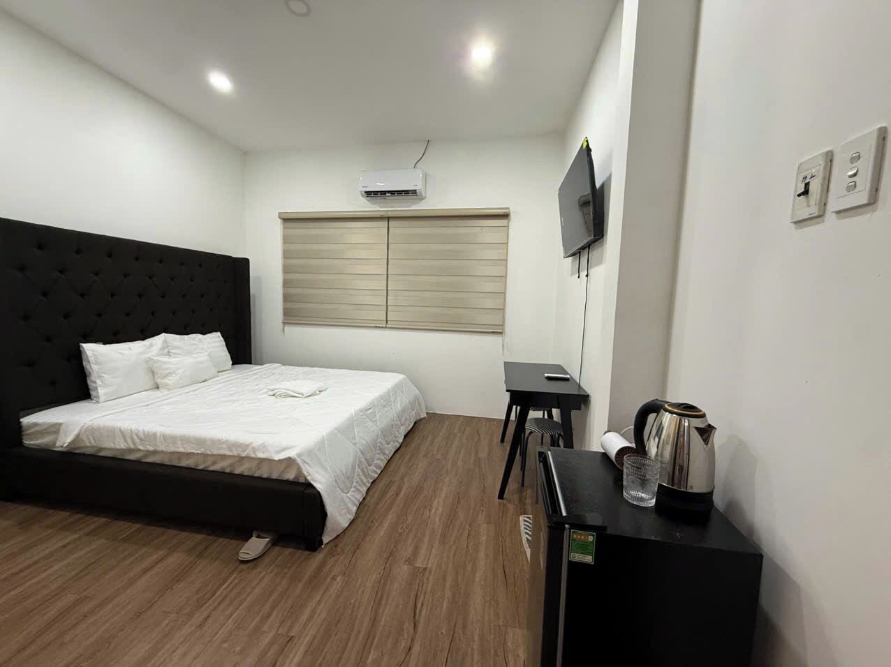 Una habitación de hotel con cama, escritorio, televisión y zona de kitchenette.