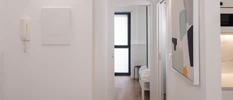 A hallway with a telephone, a door leading to a room, and a small table with towels.