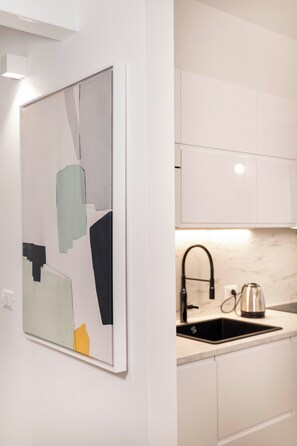 A modern kitchen with white cabinetry, a black sink, and a stainless steel kettle. - "42 square meters"A STYLISH BRAND-NEW FLAT IN THE CITY CENTER IDEAL FOR FAMILIES (BARI)