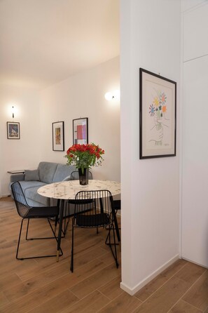 A dining area with a round table, chairs, a vase with flowers, and framed artwork on the wall. - "42 square meters"A STYLISH BRAND-NEW FLAT IN THE CITY CENTER IDEAL FOR FAMILIES (BARI)