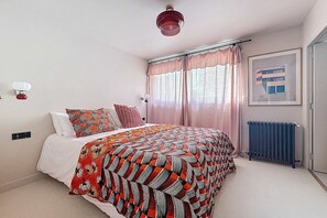 A bedroom with a bed, a radiator, a window with curtains, and a wall-mounted light fixture. - Spacious flat in the heart of Deauville (Deauville)