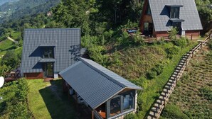 Una casa moderna con techo inclinado, un gran ventanal y una terraza de madera.