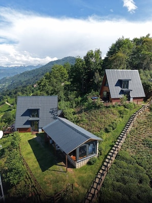 Una casa moderna con techo inclinado, un gran ventanal y una terraza de madera.
