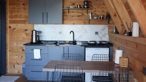 Una cocina compacta con paredes de madera, una encimera de mármol y un comedor con sillas metálicas.