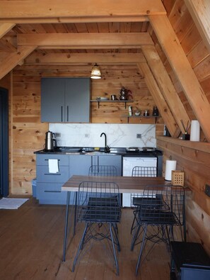 Una cocina compacta con paredes de madera, una encimera de mármol y un comedor con sillas metálicas.