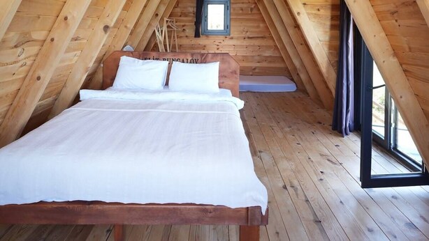 Un dormitorio estilo ático con cama, lámpara colgante y ventana.