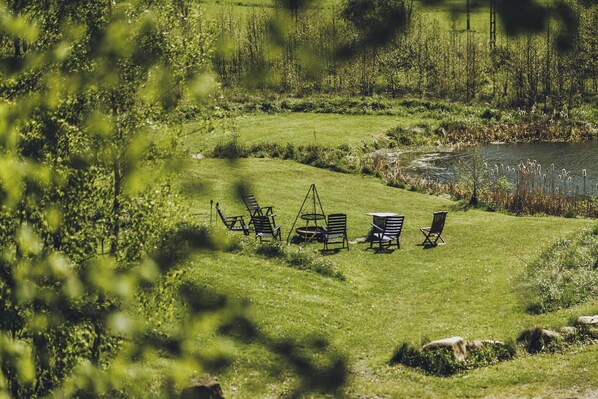 A grassy area with outdoor seating and a pond.