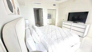Ein Schlafzimmer mit einem Bett, einem Fernseher auf einer Kommode und einem begehbaren Kleiderschrank.