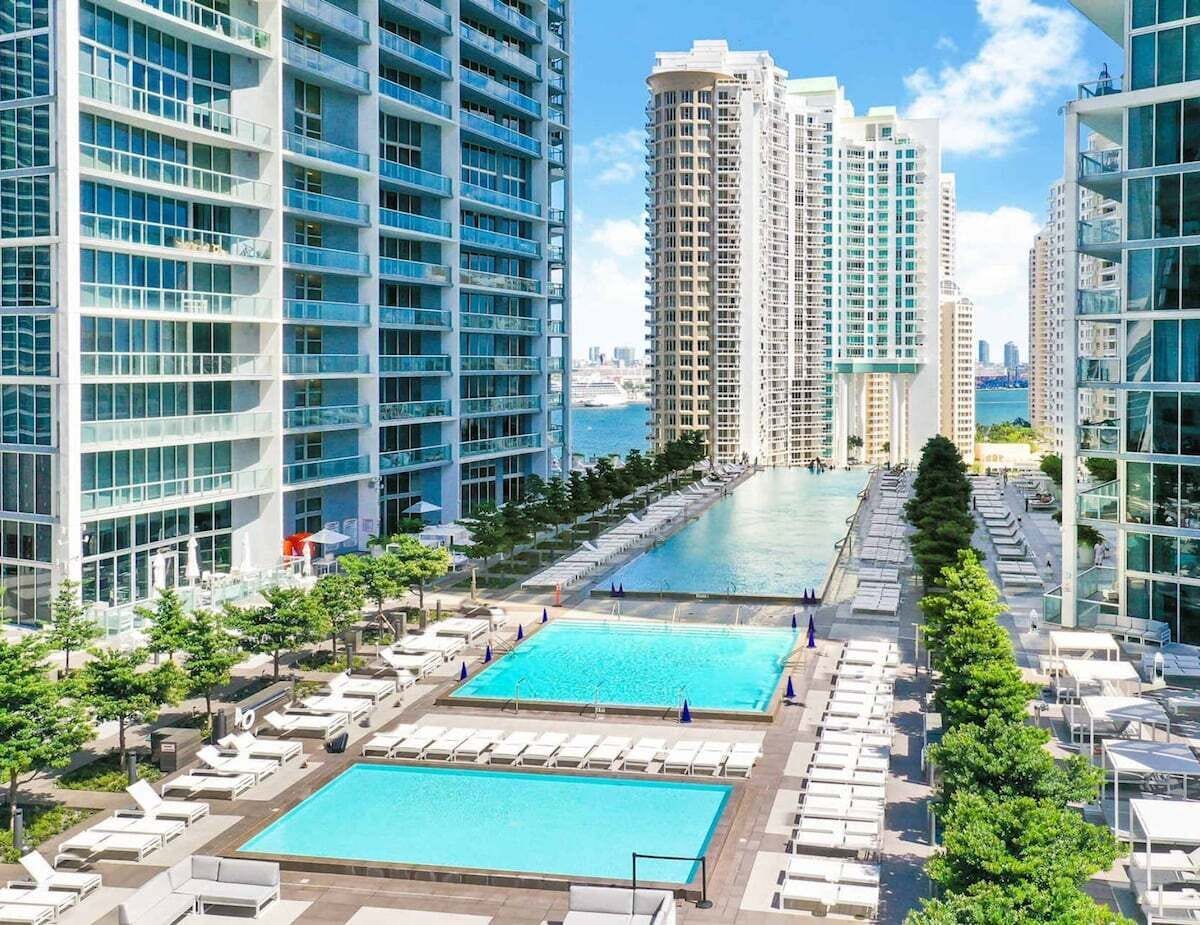 A high-rise building with a rooftop pool area, multiple balconies, and a view of the sea.