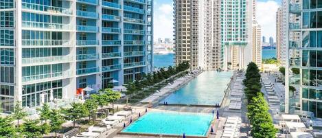 A high-rise building with a rooftop pool area, multiple balconies, and a view of the sea.