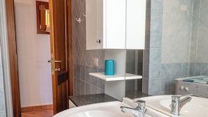 A bathroom with a white sink, a mirror, and a shower area. - Charming 3-bedroom Apartment in Santa Teresa Gallura (Santa Teresa di Gallura)