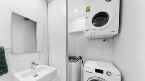 A modern bathroom with a sink, mirror, and stacked washer and dryer. - Designer 1-Bed Apartment with Balcony (Rozelle)