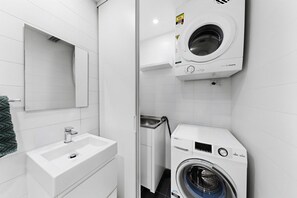 Ein modernes Badezimmer mit Waschbecken, Spiegel und gestapelter Waschmaschine und Trockner.