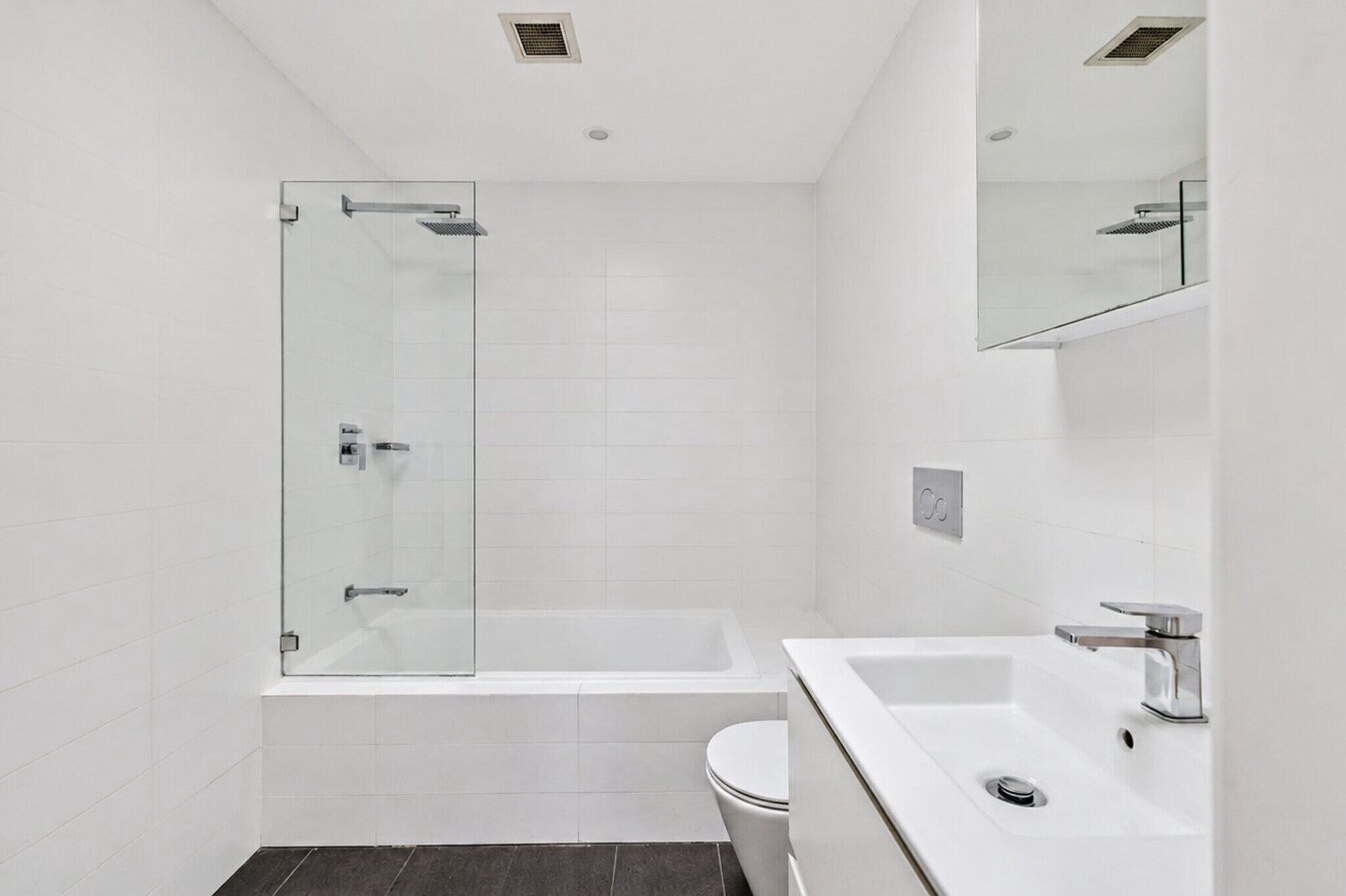 A modern bathroom with a glass-enclosed shower, a white bathtub, and a white sink with a mirror above.