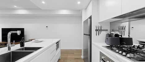 Uma cozinha moderna com armários brancos, eletrodomésticos de aço inoxidável e uma ilha central com pia.