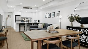 A modern living space with a dining area, kitchen, and seating. - Designer 1-Bed Apartment with Balcony (Rozelle)