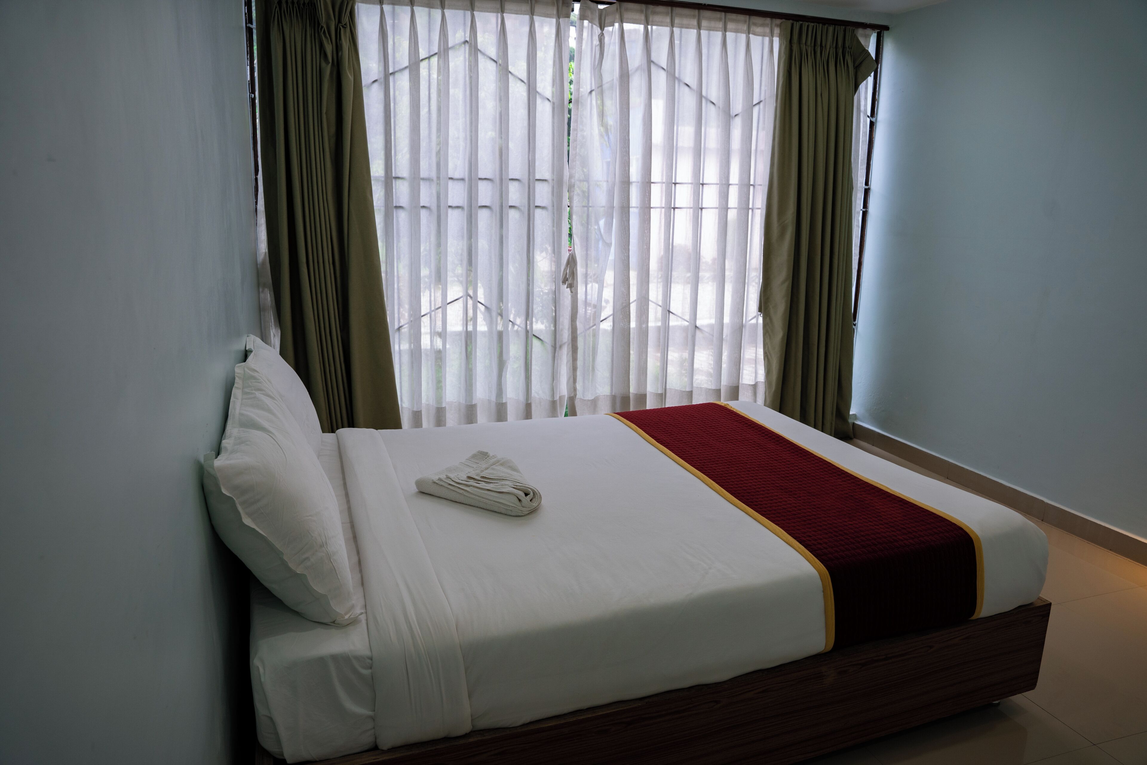 A hotel room with a bed, curtains, and a window.