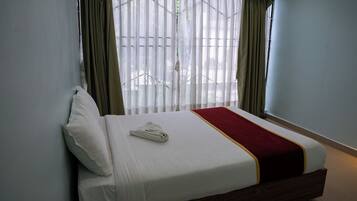 A hotel room with a bed, curtains, and a window.