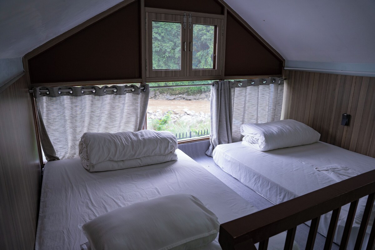 Een slaapkamer met twee bedden, een raam en uitzicht op een natuurlandschap.