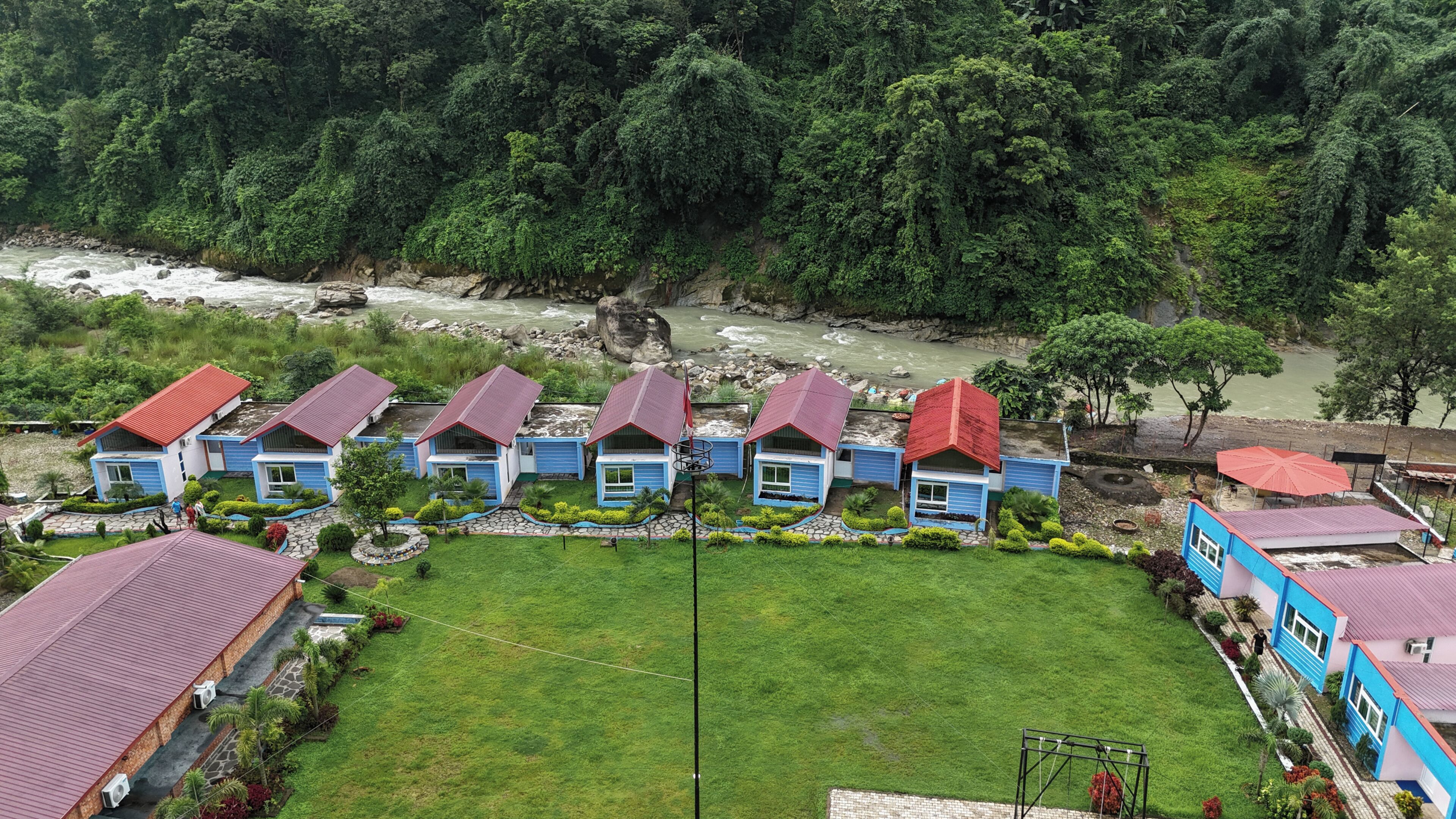 Una hilera de casas con techos azules y rojos, con un río al fondo.