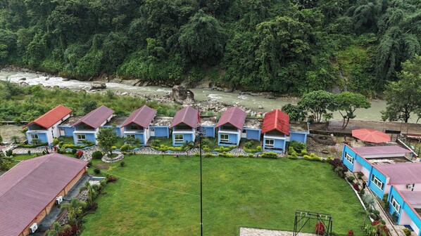 A row of blue and red-roofed houses with a river in the background.