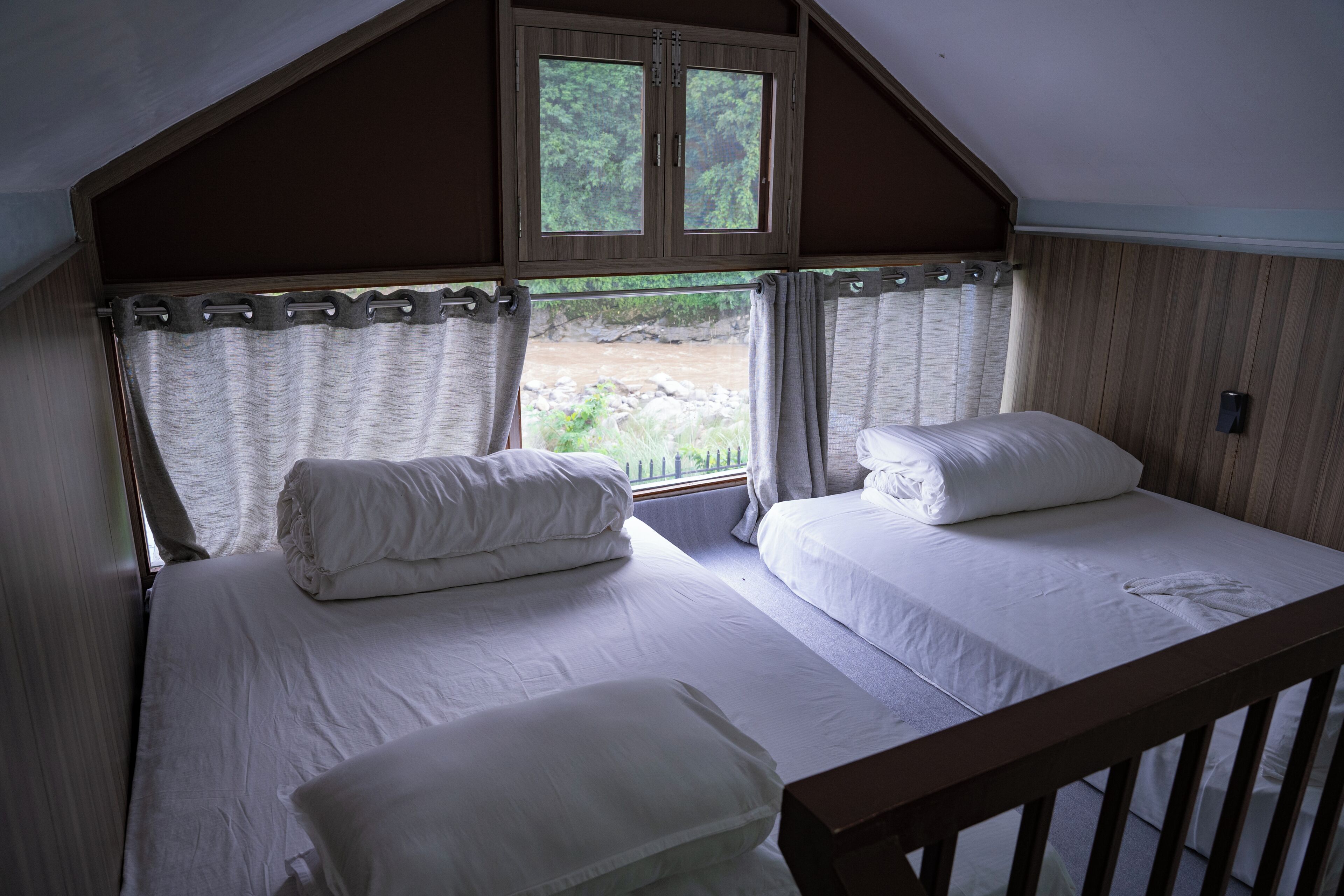 Un dormitorio con dos camas, una ventana y vistas a un paisaje natural.