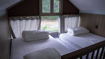 Un dormitorio con dos camas, una ventana y vistas a un paisaje natural.