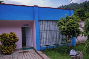 A building with a blue and pink exterior, a door labeled 'SWEET ROOM-7,B.', and a window with a geometric pattern.