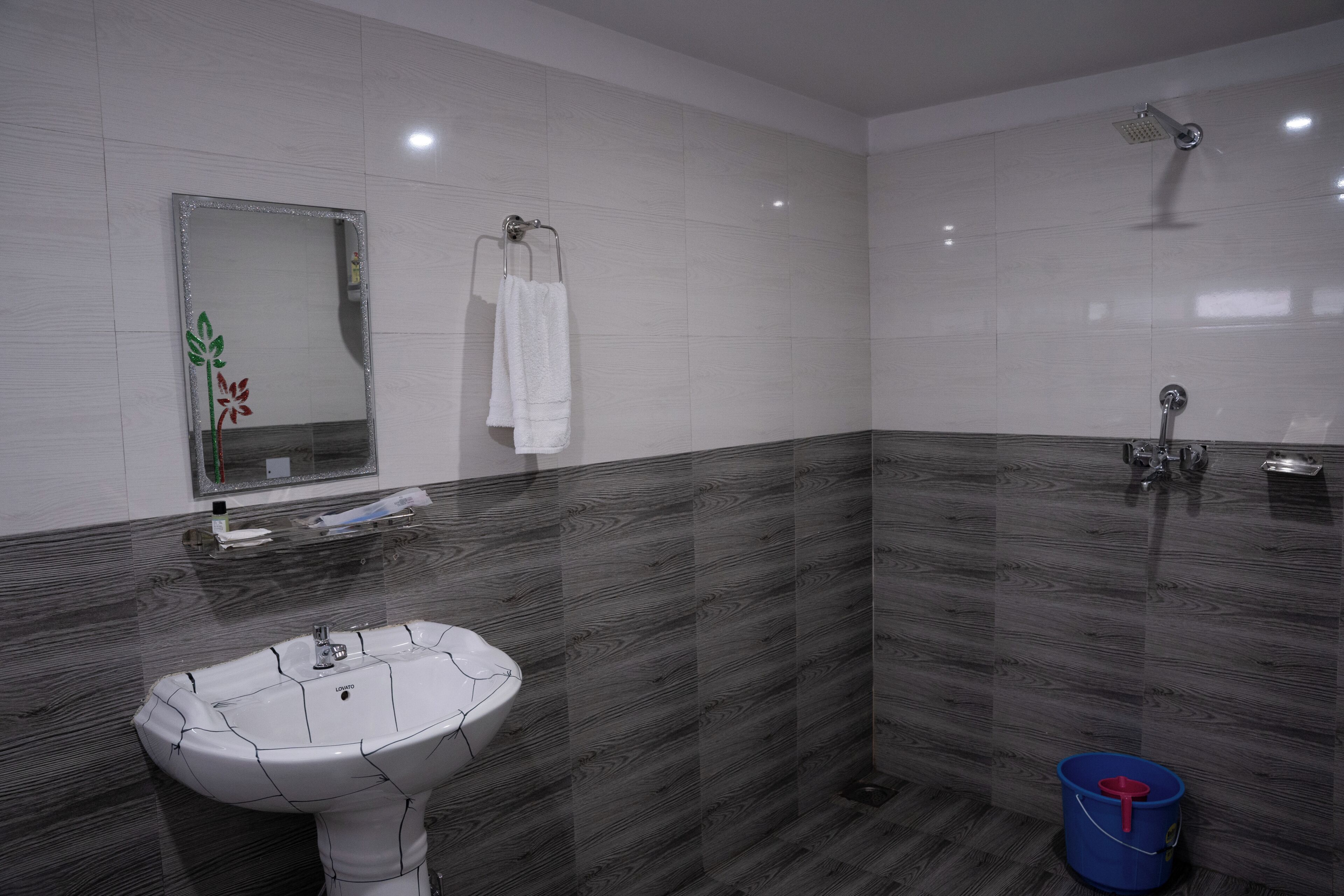 A modern bathroom with a white sink, a mirror, and a shower.