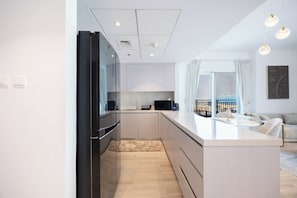 A modern kitchen with a black refrigerator, white cabinets, and a light-colored countertop. - Bloomfields 3BR plus maid in Waters Edge (Abu Dhabi)