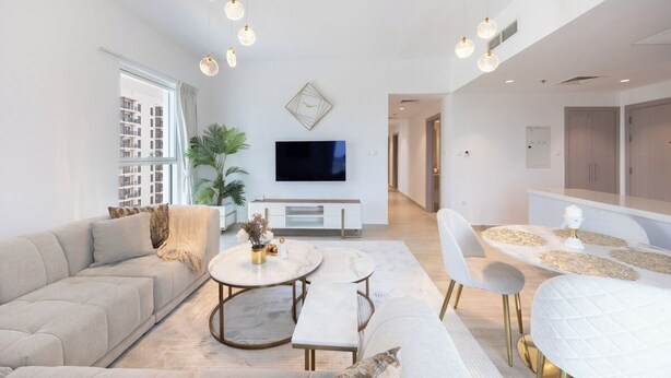 A modern living room with a sofa, coffee table, and dining area. - Bloomfields 3BR plus maid in Waters Edge (Abu Dhabi)