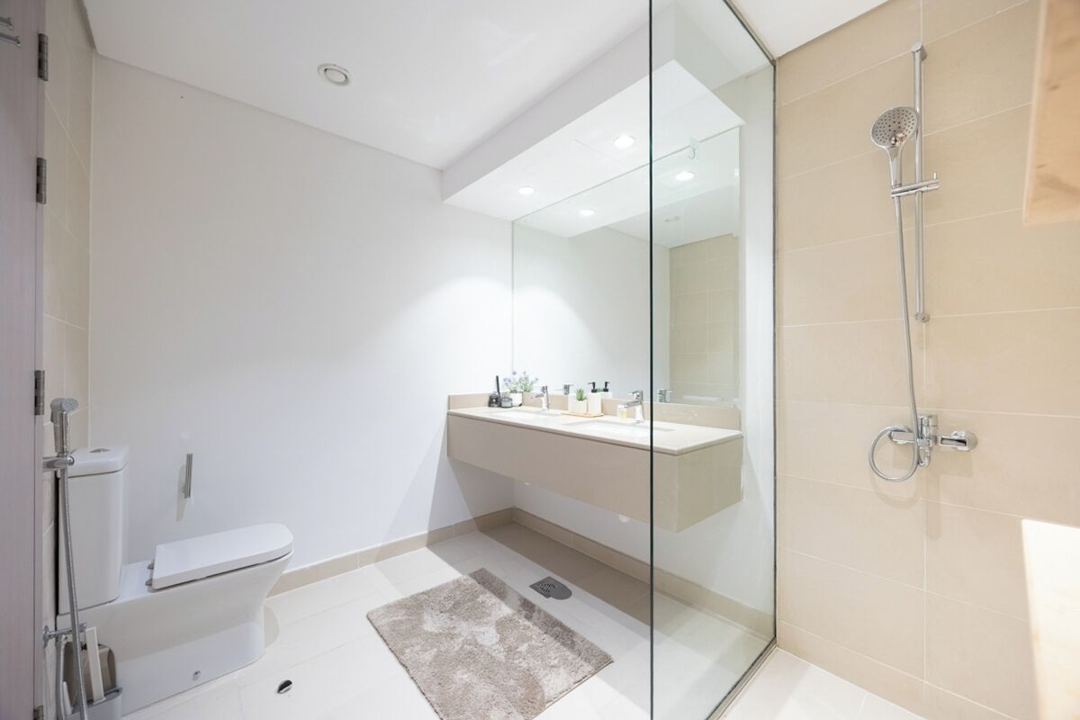 A modern bathroom with a glass shower enclosure, a toilet, and a vanity with a mirror.